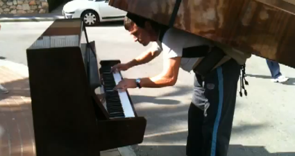 VIDEO: Man Plays Piano While Balancing Another Piano on His Back