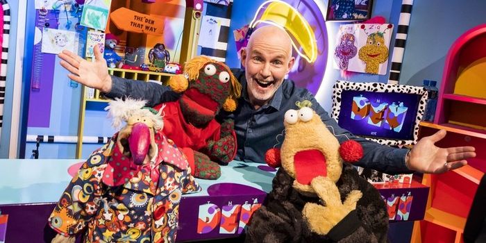 A still from The Den. Host Ray D'Arcy stands with his arms over three puppets.
